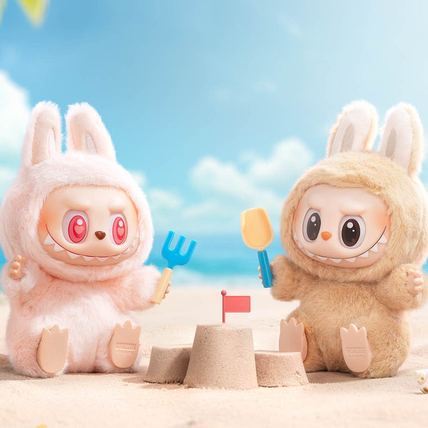 Two cartoonish Pop Mart Labubu on a beach with sandcastles and toys.
