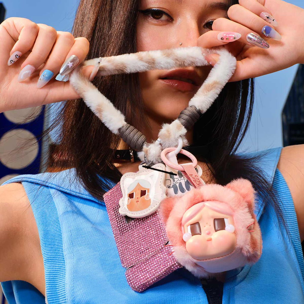 Person holding a Pop Mart Labubu phone case with cartoon character design against a blue background
