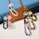Pop Mart Labubu keychains with cartoon faces attached to a brown handbag on a white surface.