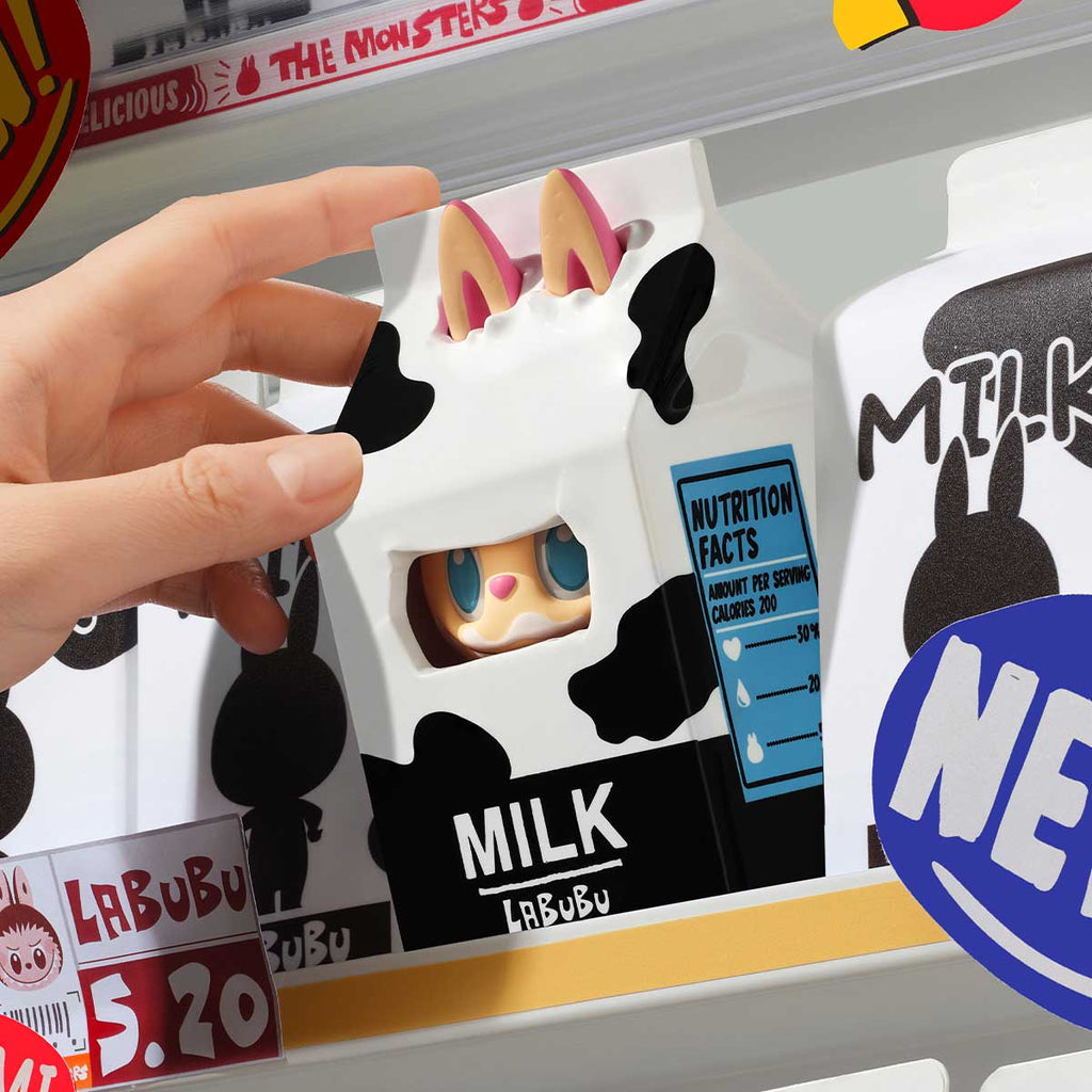 Hand holding a Pop Mart Labubu with packaging labeled 'Milk Labubu' against a blurred background.