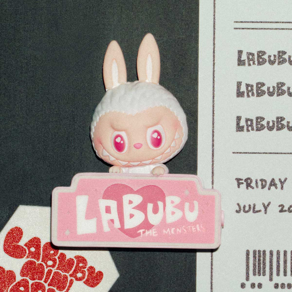 Pop Mart the Labubu Monsters with bunny ears and pink heart eyes, standing on a pink platform with 'LABUBU' branding.