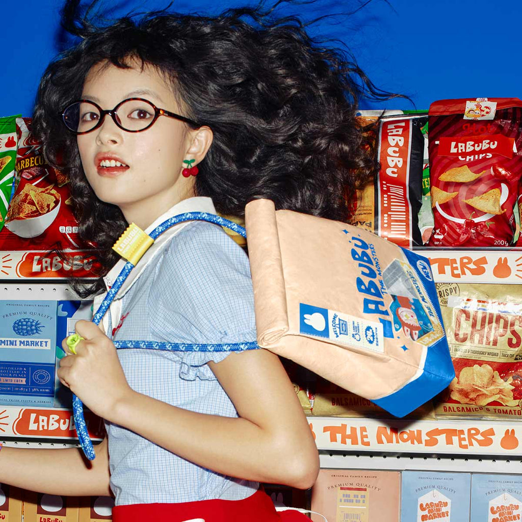 Person with curly hair and glasses surrounded by Labubu Monsters snack packages