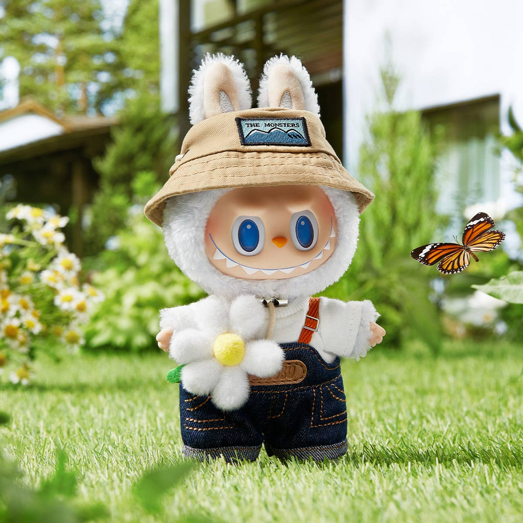 Pop Mart the Labubu Monsters with bunny ears and a hat standing on grass with a butterfly and flowers in the background