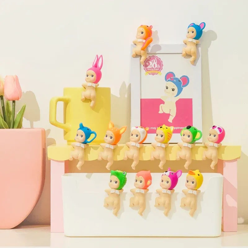 Colorful Sonny Angels Looking Back on a stand with a mug and decorative items in the background.
