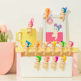 Colorful Sonny Angels Looking Back on a stand with a mug and decorative items in the background.