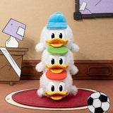 Stacked plush toys of Donald Duck in a room setting with a lamp and soccer ball.