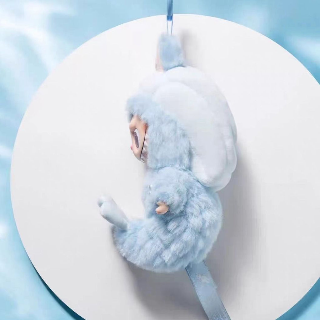 Blue Labubu plush toy resembling a dragon on a white plate with a blue background